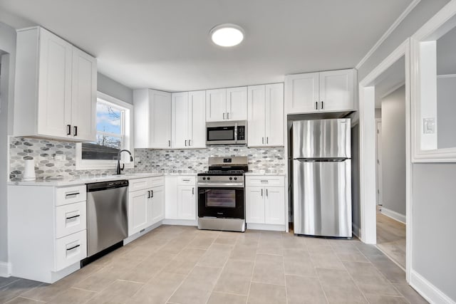 kitchen featuring appliances with stainless steel finishes, backsplash, crown molding, sink, and white cabinets