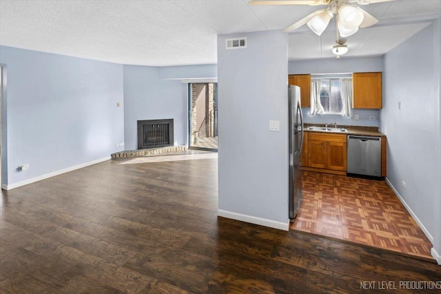 kitchen featuring a textured ceiling, stainless steel appliances, ceiling fan, sink, and dark hardwood / wood-style floors