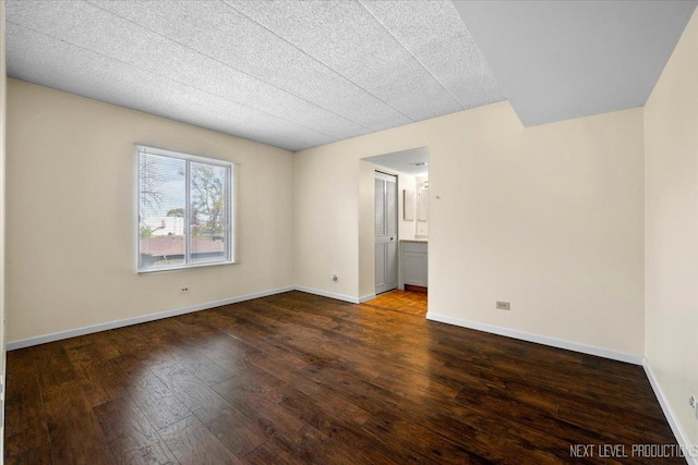 spare room featuring a textured ceiling and dark hardwood / wood-style floors