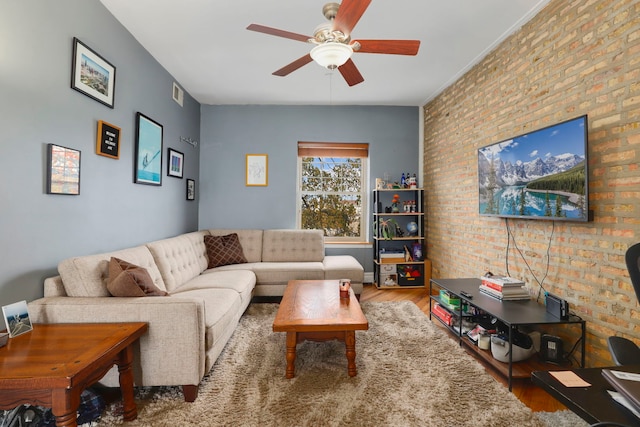 living room with ceiling fan, wood-type flooring, and brick wall