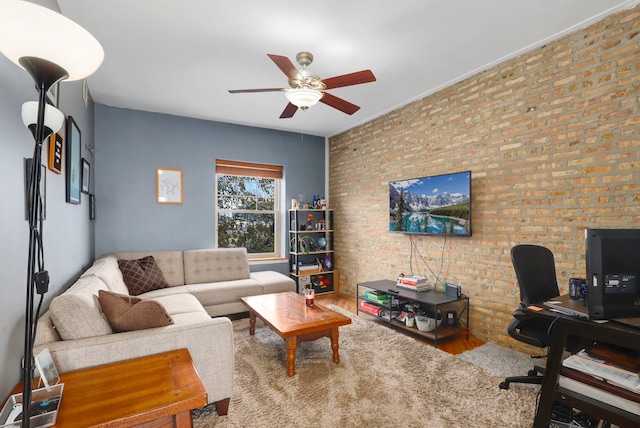 living room featuring ceiling fan, hardwood / wood-style floors, and brick wall