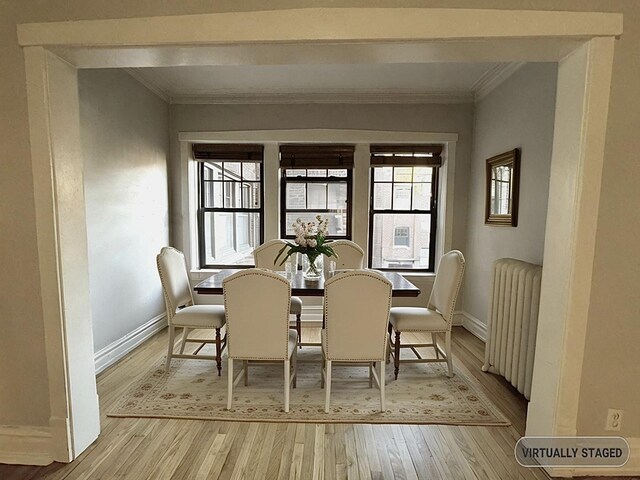 dining space featuring light hardwood / wood-style flooring, radiator, and ornamental molding