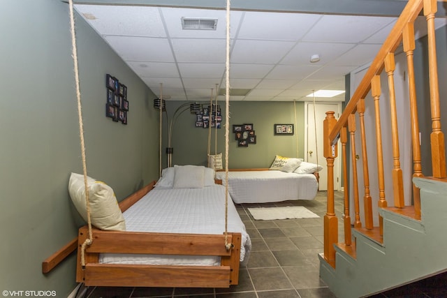 bedroom with a paneled ceiling and dark tile patterned flooring