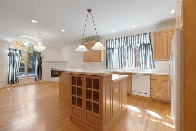 kitchen with decorative light fixtures, a center island, light wood-type flooring, and white appliances