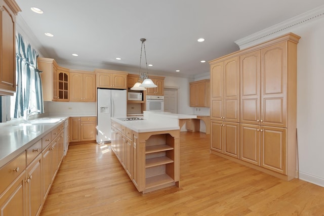 kitchen with a center island, decorative light fixtures, white appliances, and light wood-type flooring