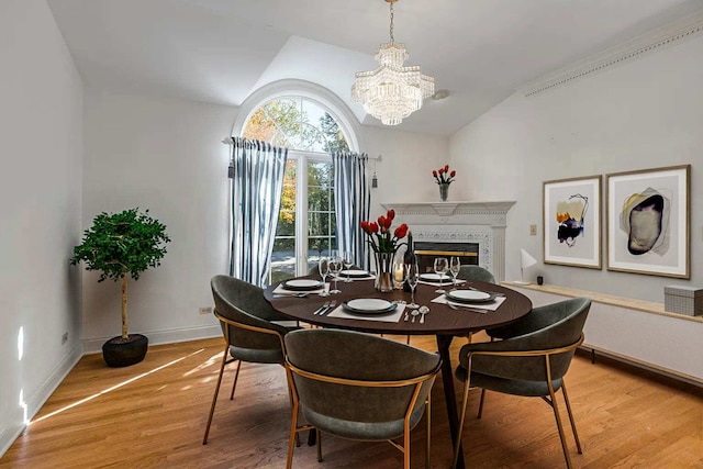 dining area with an inviting chandelier, light hardwood / wood-style floors, and vaulted ceiling