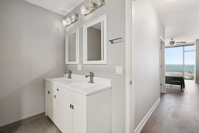 bathroom featuring hardwood / wood-style floors, vanity, a water view, ceiling fan, and a wall of windows