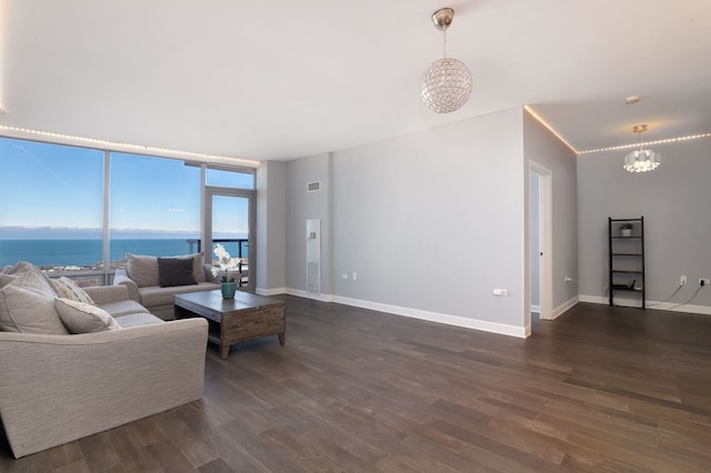 living room featuring dark hardwood / wood-style flooring, a water view, and a notable chandelier