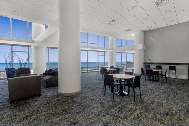 carpeted dining room with a drop ceiling, a water view, and a high ceiling