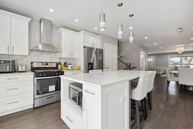 kitchen with white cabinets, dark wood-type flooring, wall chimney range hood, and appliances with stainless steel finishes