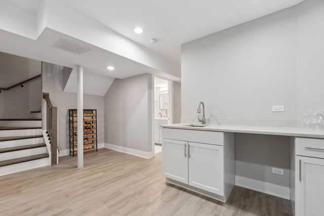 interior space with white cabinets, light hardwood / wood-style floors, lofted ceiling, and sink