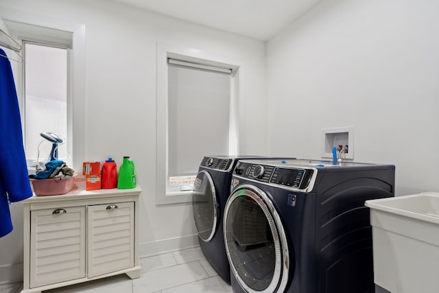 laundry room featuring washer and dryer, light tile patterned flooring, and sink