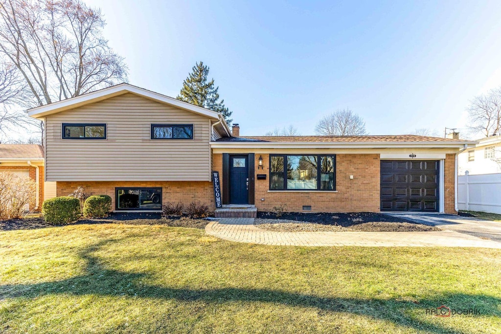 split level home with a garage and a front lawn