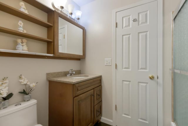 bathroom with a shower with door, vanity, and toilet