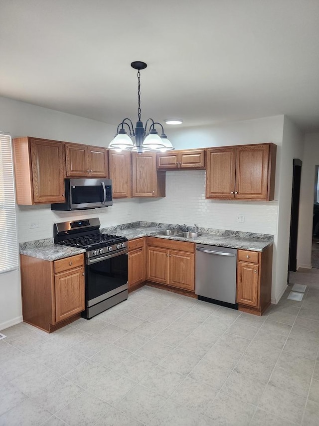 kitchen featuring sink, decorative light fixtures, appliances with stainless steel finishes, a notable chandelier, and light tile patterned flooring