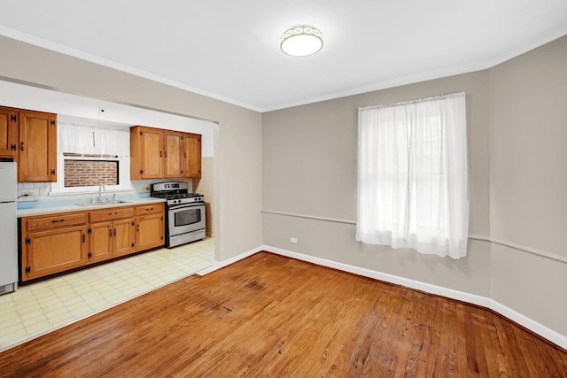 kitchen featuring decorative backsplash, sink, a healthy amount of sunlight, and stainless steel range with gas stovetop