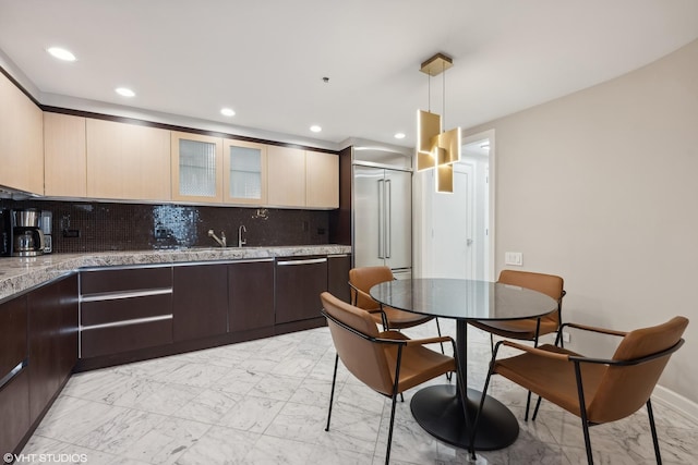 kitchen with dark brown cabinetry, dishwasher, sink, hanging light fixtures, and decorative backsplash