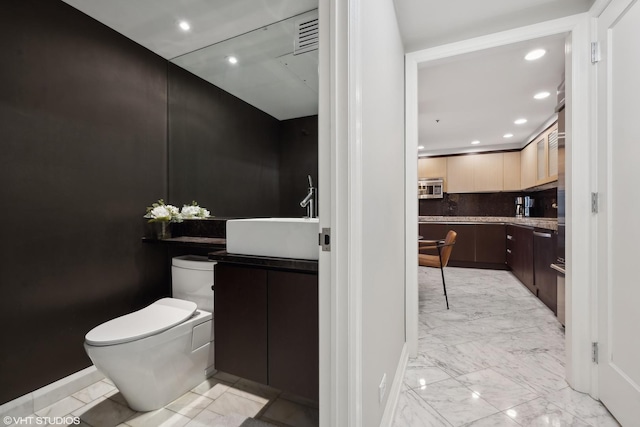 bathroom featuring vanity, tasteful backsplash, and toilet