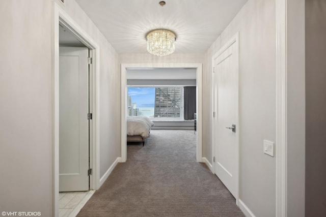 hall with carpet and an inviting chandelier