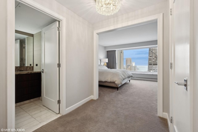 bedroom with a chandelier, connected bathroom, and light colored carpet