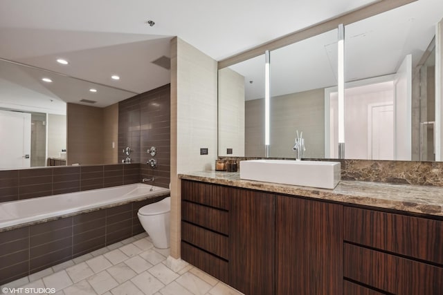 bathroom featuring vanity, toilet, and tiled tub