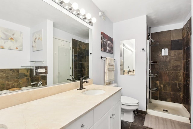 bathroom with tile patterned flooring, vanity, toilet, and tiled shower