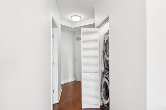 laundry area featuring stacked washing maching and dryer and dark wood-type flooring