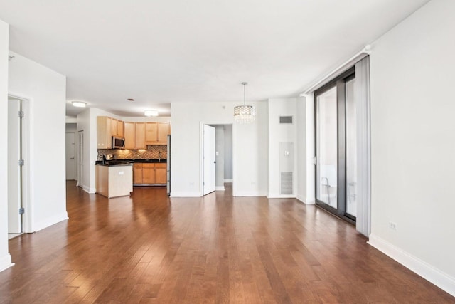 unfurnished living room featuring dark hardwood / wood-style floors, an inviting chandelier, and a healthy amount of sunlight