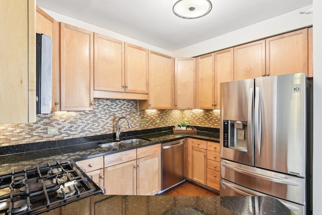 kitchen featuring appliances with stainless steel finishes, light brown cabinets, dark stone countertops, and sink