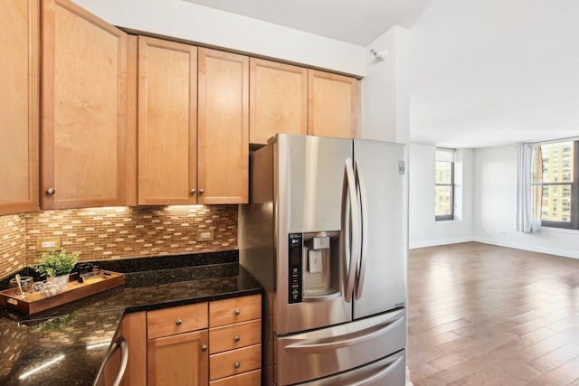 kitchen with decorative backsplash, dark stone countertops, stainless steel refrigerator with ice dispenser, and dark wood-type flooring