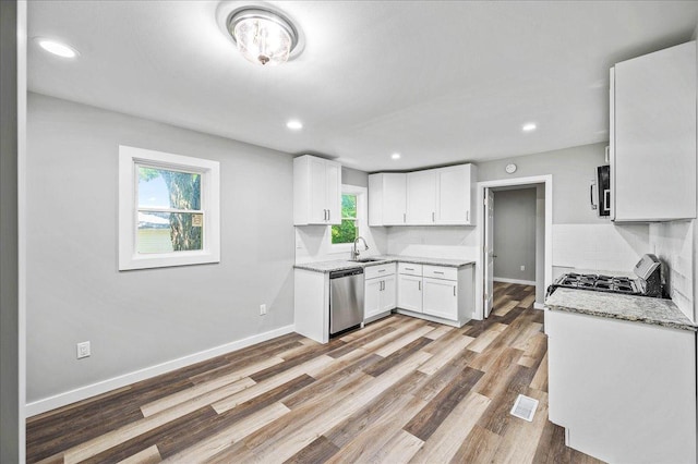 kitchen featuring appliances with stainless steel finishes, light stone counters, sink, light hardwood / wood-style flooring, and white cabinets