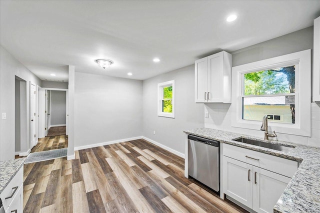 kitchen featuring dishwasher, sink, light stone counters, white cabinets, and hardwood / wood-style flooring