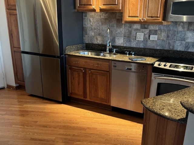 kitchen featuring sink, light hardwood / wood-style flooring, stainless steel appliances, and stone countertops