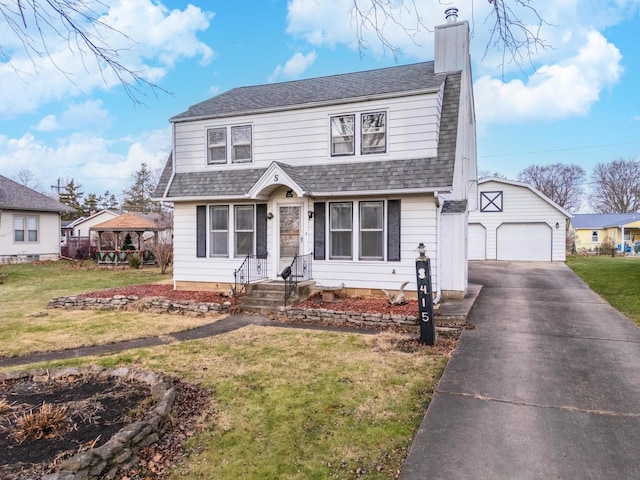 view of front of home featuring a front yard, a garage, and an outdoor structure