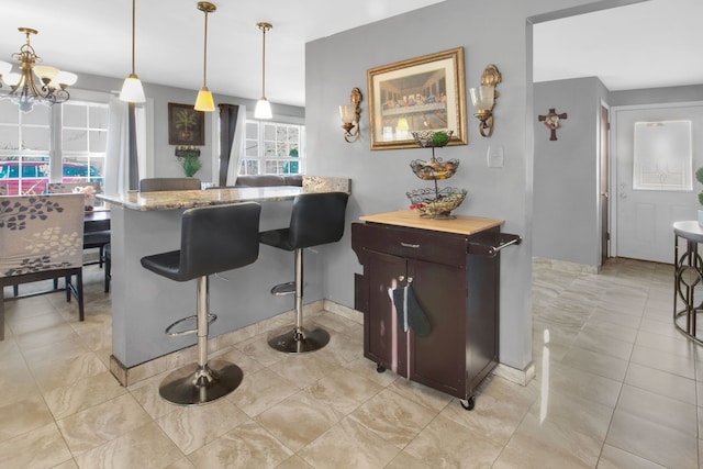 kitchen with a kitchen breakfast bar, hanging light fixtures, light tile patterned floors, a notable chandelier, and kitchen peninsula