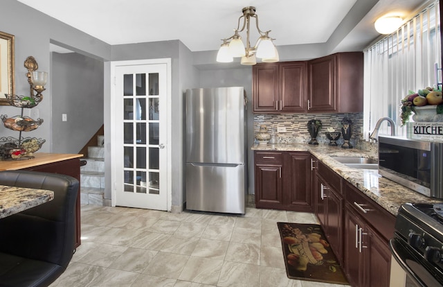 kitchen with light stone countertops, stainless steel appliances, sink, pendant lighting, and a chandelier