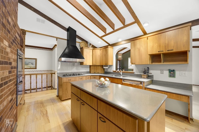 kitchen featuring vaulted ceiling, a kitchen island, brick wall, and wall chimney range hood