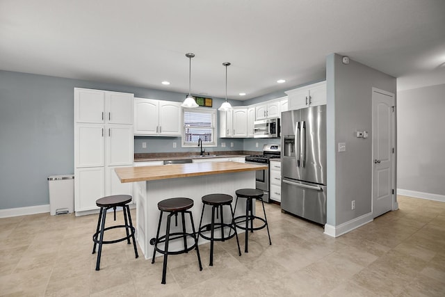 kitchen with a center island, wooden counters, white cabinets, appliances with stainless steel finishes, and decorative light fixtures