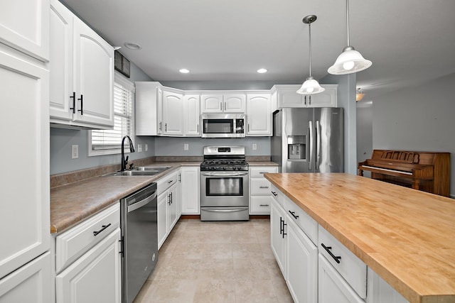 kitchen featuring wooden counters, stainless steel appliances, white cabinetry, and sink