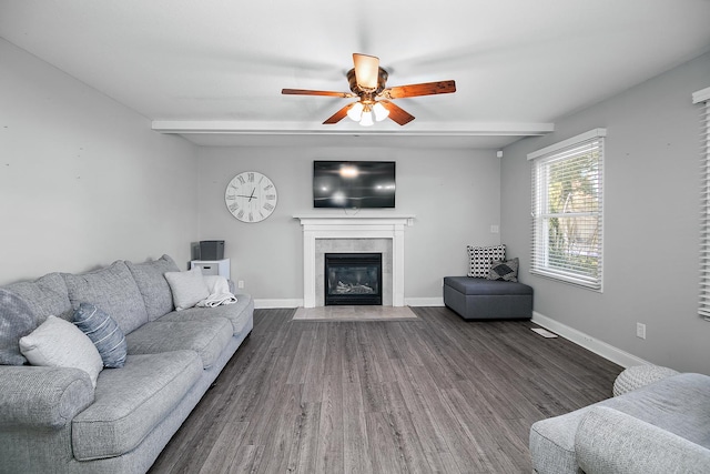 living room featuring dark hardwood / wood-style floors, ceiling fan, and a tiled fireplace