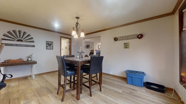 dining area featuring light wood-type flooring, an inviting chandelier, and crown molding