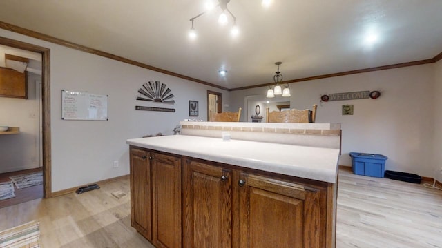 kitchen featuring light wood-type flooring, a center island, hanging light fixtures, and crown molding