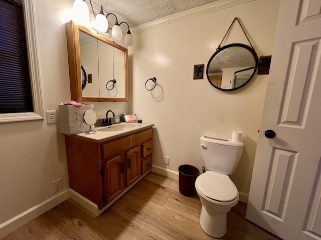 bathroom with vanity, a textured ceiling, crown molding, hardwood / wood-style flooring, and toilet