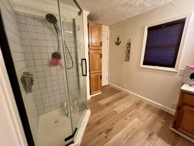 bathroom featuring vanity, wood-type flooring, a textured ceiling, and a shower with shower door