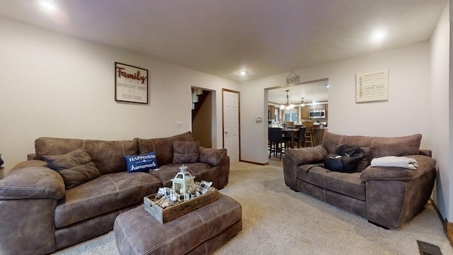 carpeted living room with an inviting chandelier