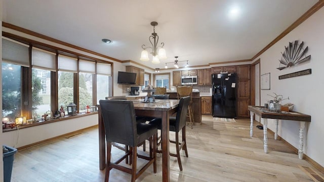 dining space with crown molding, light hardwood / wood-style flooring, and an inviting chandelier