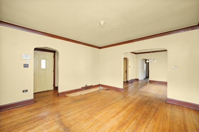 unfurnished living room featuring a notable chandelier, wood-type flooring, and ornamental molding