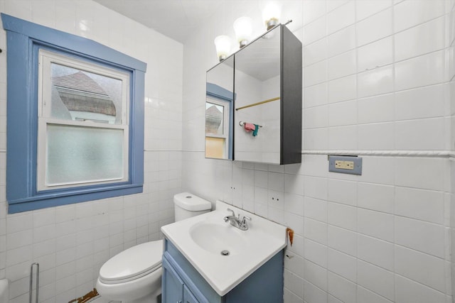 bathroom featuring vanity, toilet, and tile walls