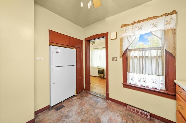 kitchen featuring ceiling fan, white fridge, and heating unit