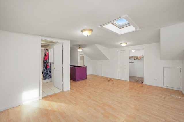 additional living space featuring a skylight and light hardwood / wood-style flooring